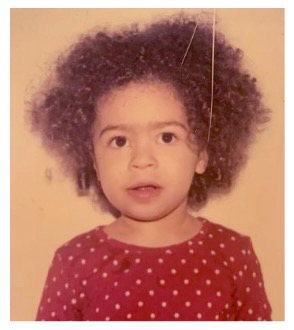 Image of a young Shelby with tight nit curls in a loose fro