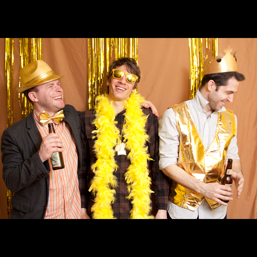 Three guys wearing gold props and drinking sharing a laugh.