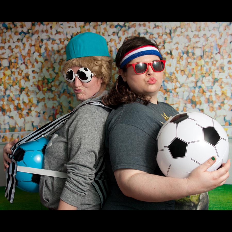 Two ladies in sporty outfits with soccer props.
