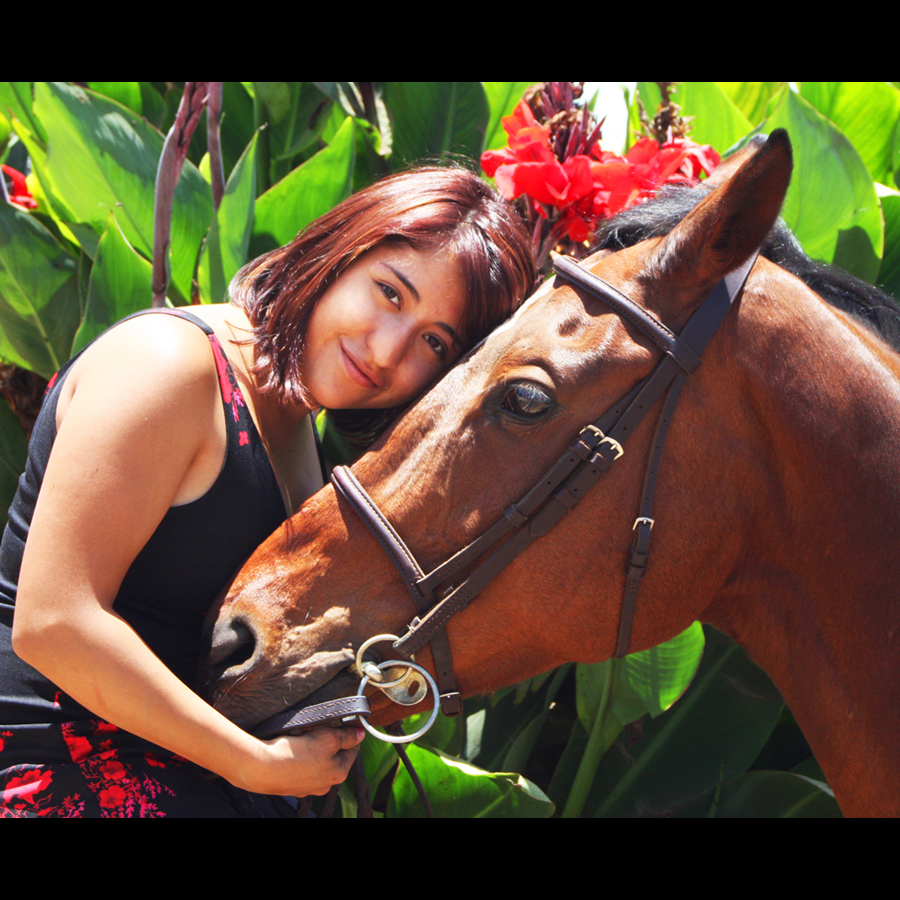 Woman lays her head on her horse's head while hugging him to her chest.