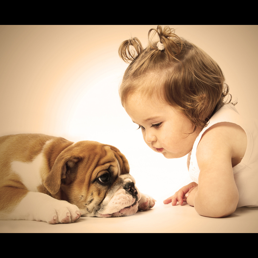 A littler girl and  puppy are laying down facing eachother.