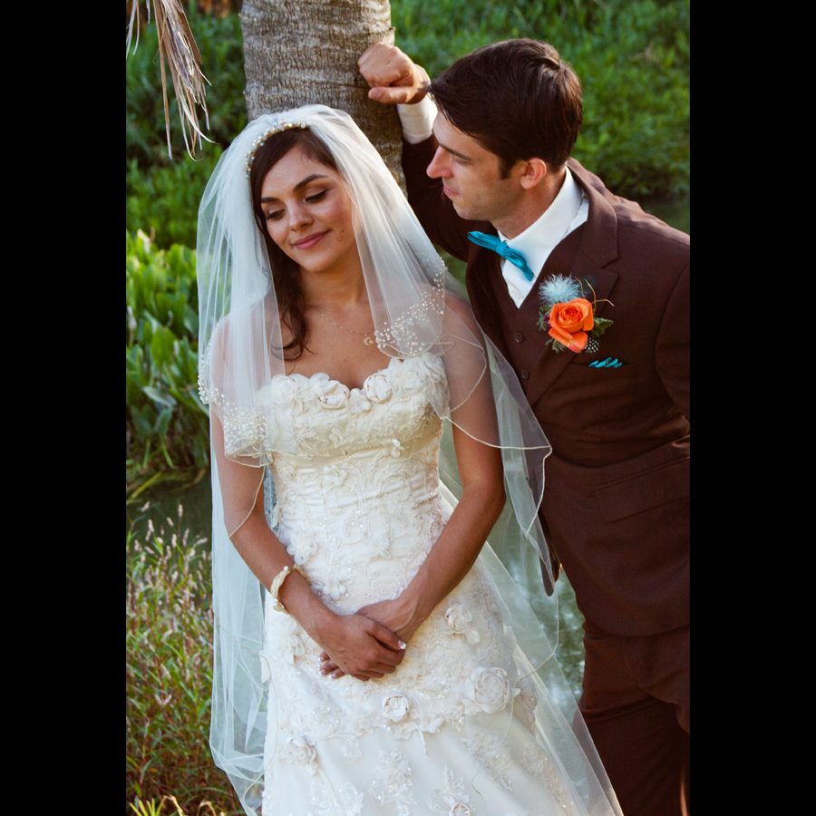 Bride and groom leaning against a tree.