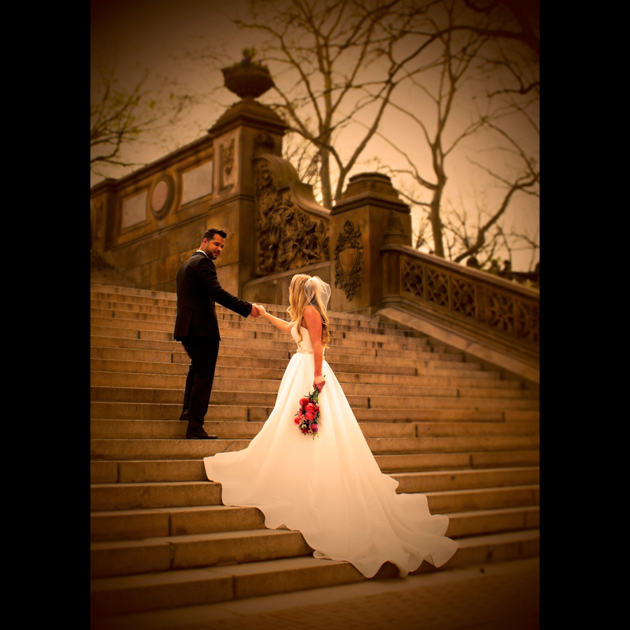 Groom helping his bride up the stairs with her dress train flowing down behind her.