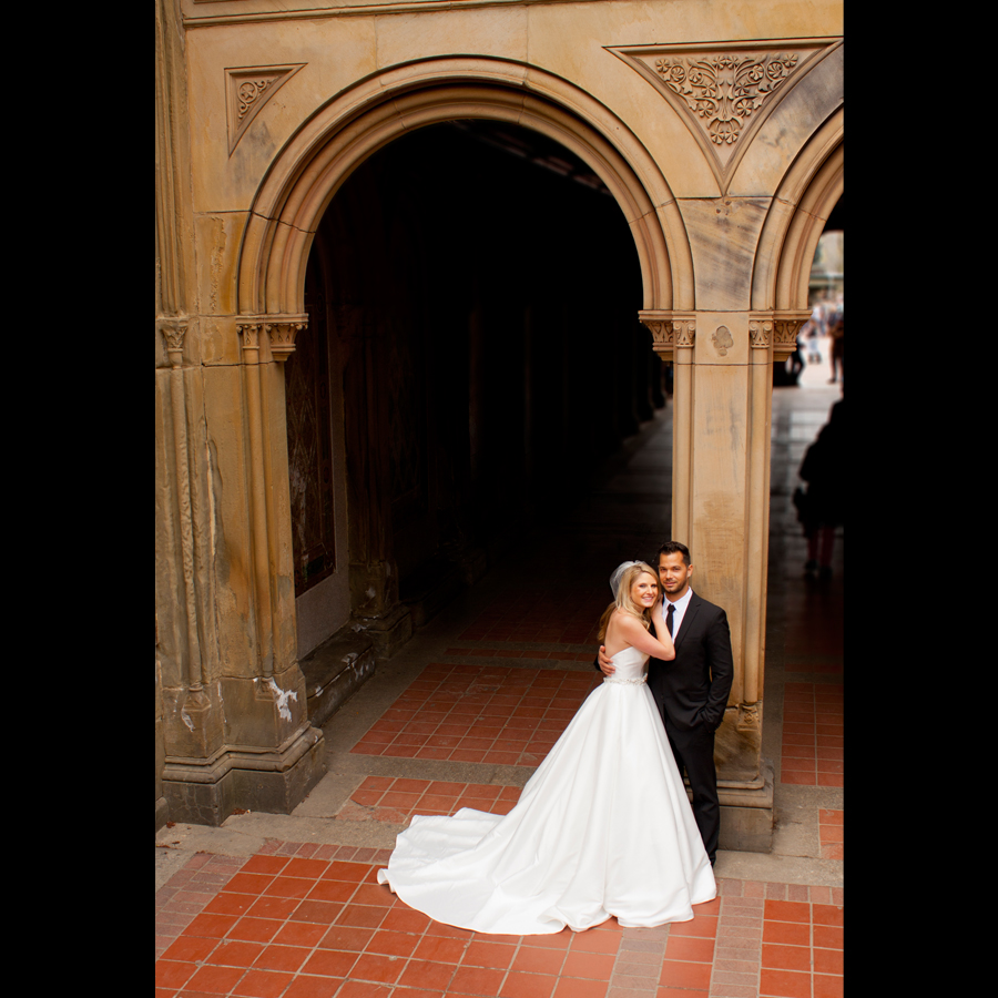 Bride and groom portrait posing under an archway.