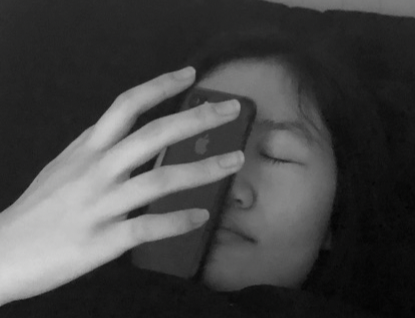 a close photo of hyacinth weng, with her phone on her face and her hand hovering over the phone