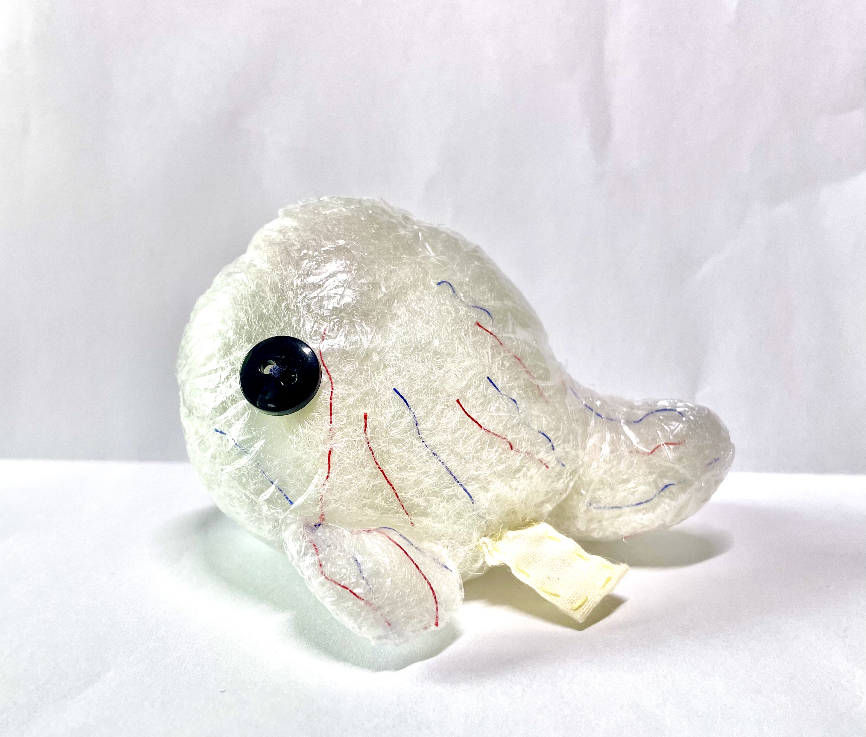 clear whale made out of thin transparent plastic instead of felt with red and blue viens of thread within the stuffing