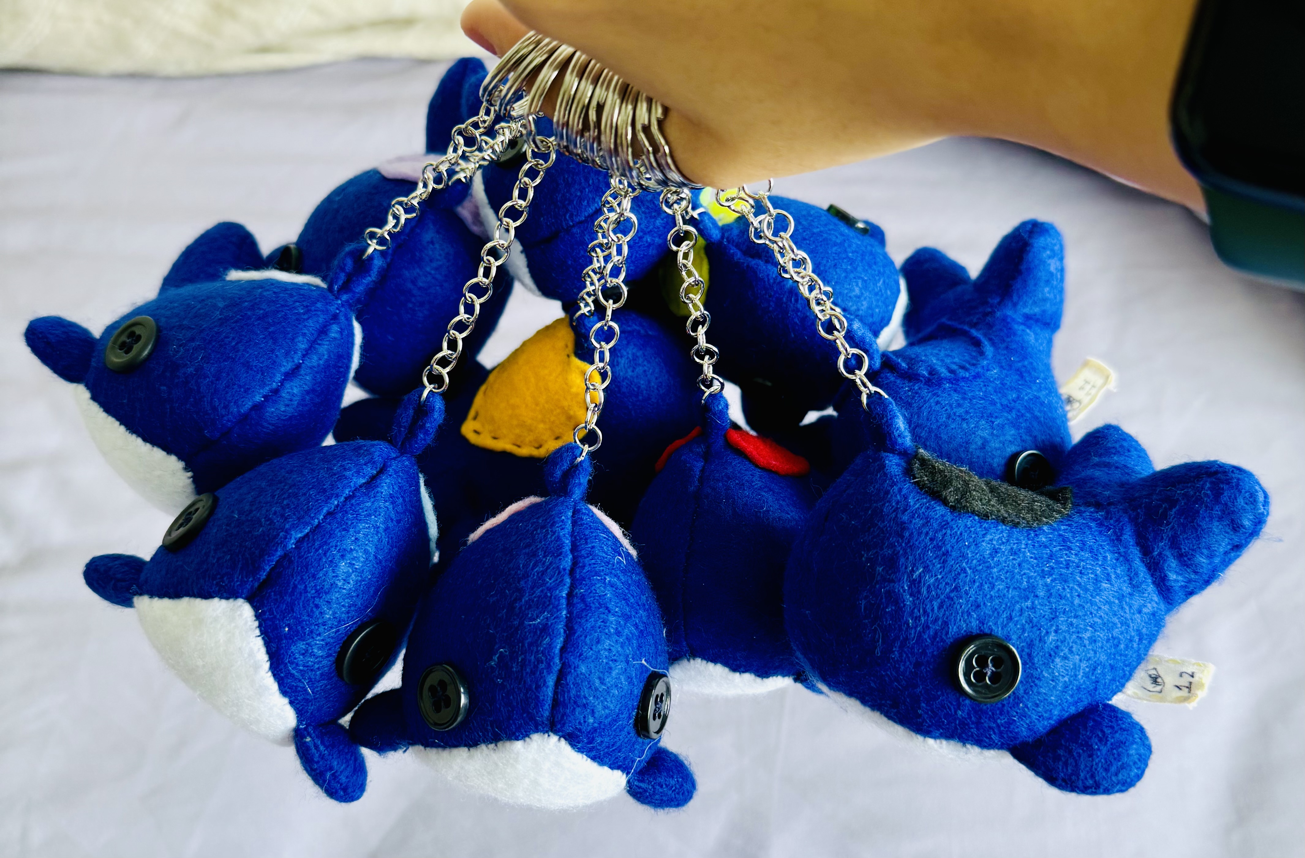 A handful of keychain whales hooked on a thumb and hanging down